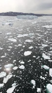 İnsansız hava aracı yüzen buzun üzerinden Grönland kütlesi ve bulutlu Kuzey Kutbu ufkuna doğru ilerliyor..