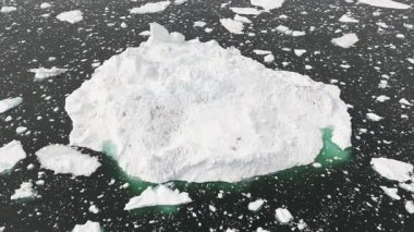 İHA, Ilulissat yakınlarındaki kopuk bir buzdağının etrafında döner ve sakin kutup sularına karşı yontulmuş buz dokularını ortaya çıkarır..