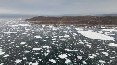 İnsansız hava aracı buzla dolu denizin üzerinde ilerler sonra yavaşça alçalır ve yüzen kutup buzullarının tepeden aşağı görüntüsüyle son bulur..