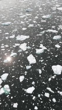 Dikey İHA buzun üzerinden aşağı doğru başlıyor, sonra da dev bir buzdağı ve Grönland Arktik kıyı şeridini ortaya çıkararak yukarı doğru eğiliyor..