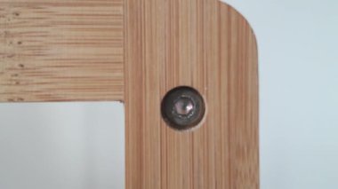 Sıcak makro zoom, ahşap yapı yüzeyinde kablosuz elektrikli matkap sürücüsü tarafından işaretlenmiş Allen vidasını gösteriyor..