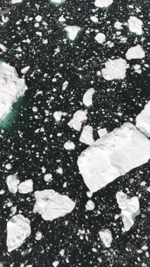 Kameralar ilerlerken yukarı doğru eğilir, yoğun yüzen buzdan parlak kutup gününde çorak Grönland 'a geçiş yapar.