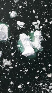 Yavaşça yukarı doğru hareket et ve saat yönünün tersine dön. Soğuk Grönland sularında yüzen sayısız buz parçasını açığa çıkar.