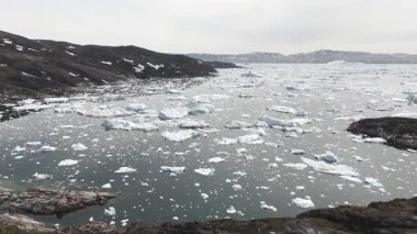 Verimsiz Grönland arazisinden kayan buz parçalarıyla dolu sakin sulara doğru ilerliyorlar.