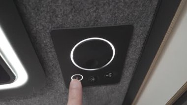 Bir kullanıcının aydınlatma tuşlarını beyaz kenarlı, modern bir siyah akıllı ışıklandırma denetleyicisine vuruşunun üst açılı görünümü