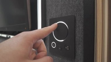 Kullanıcı, aydınlatma düğmesini siyah aygıtın ana hatlarını belirleyen yumuşak beyaz ışığı gösteren akıllı bir aydınlatma kontrol panelinde döndürür