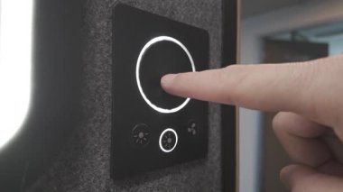 Kullanıcı, akıllı ışıklandırma kontrolörünün sol tarafındaki düğmelerle etkileşime girer ve kontrollerin etrafındaki yumuşak beyaz ışığı etkinleştirir.