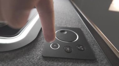 Düşük açılı çekim, aydınlatmalı elementleri karanlık bir iç mekanda hafifçe parlarken akıllı ışıklandırma cihazını ayarlayan bir kullanıcıya odaklanıyor.