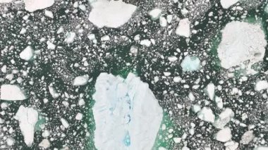 Ön hava takibi şeffaf buz dağının dokusunu, su altındaki buzu ve donmuş kutup sularında gezinen yalnız gemiyi vurgular..