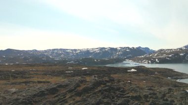 Geriye dönük hava hareketleri engebeli zemin, uzak dağlar, dağınık buzdağları ve sakin Kuzey Kutbu yaz atmosferini ortaya çıkarıyor..