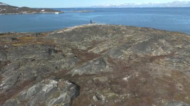 Kamera kayalık zeminden açık denize, çerçeve ölçeğine, izolasyona ve berrak yaz ışığı altında tefekküre doğru yükseliyor.