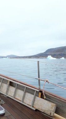 Kameralar yay boyunca engebeli kutup bölgesine bakıyor, buzla kaplı sakin deniz, Ilulissat yakınlarında uzak atmosfer ve huzur dolu.