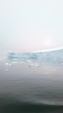 Tekne izi Grönland 'daki parçalanmış buzu sisli kutup sularında hareket ettiriyor. Çatlak donmuş yüzeyler ve yavaş ritmik hareketler ortaya çıkıyor.