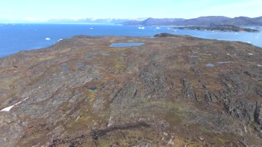Sera 'daki kayalık bir adanın üzerinde okyanusta buzdağlarıyla uçan çarpıcı hava görüntüleri.