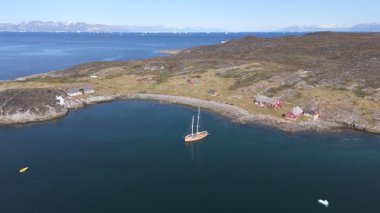 İki direkli ahşap bir yelkenlinin, Greenland 'de ıssız bir körfezde demirlediği havada dönen görüntüsü.