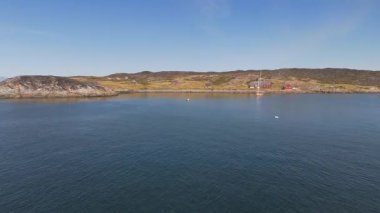 Geleneksel evleri olan uzak bir Grönland körfezinde suda yüzen küçük sarı bir tekne.