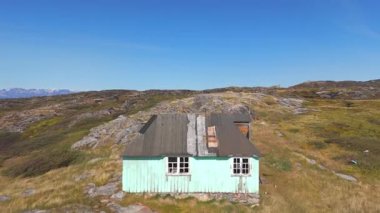 Grönland 'ın kayalık sahillerinde, deniz buzdağlarıyla terk edilmiş bir evin havadan görünüşü.