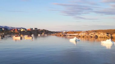 Saqqaq 'ın panoramik manzarası, Grönland kıyılarında buzdağları ve balıkçı tekneleri olan bir yerleşim yeri.