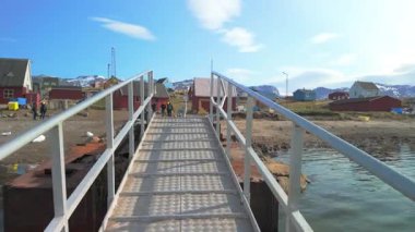 Grönland 'ın uzak kutup köyü Saqaq' taki bir rıhtıma giden bir tekneden iniyorlar.