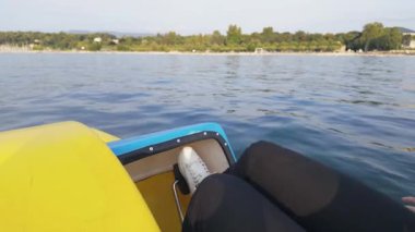 Uzakta yeşil bir kıyı şeridi olan bir gölde pedal çeviren birini ilk gören kişi.