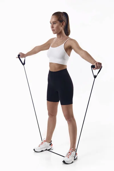 Fitness egzersizi. Beyaz arka planda izole edilmiş, direniş bandıyla spor yapan kadın.