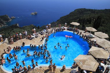 CORFU, GREECE - 8 Temmuz 2021: İnsanlar Yunanistan 'ın Korfu Adası' ndaki genel tatil tatil yüzme havuzunu ziyaret ettiler.