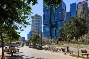 Tel Aviv 'de parkedilmiş bisikletleri, modern gökdelenleri ve güneşli bir günde açık mavi gökyüzü olan bir sokak. İsrail 'in tipik canlı iş bölgesi..