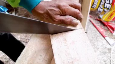 Marangoz el, inşaat onarım çalışmaları sırasında keskin metal testereyle tahta kesiyor. Uçan talaş ve kereste hazırlayan el işçiliği konsepti..