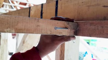 Marangoz el, el yapımı iskelet işleri, konut yenileme ve ahşap marangozluk montaj sırasında balta başlı aletle ahşap kiriş yapısına metal çivi çakıyor..