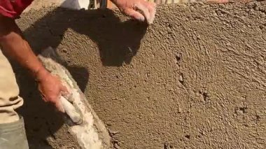 Geleneksel inşaat işlerini bitirmek için duvarı malayla kaplayan, ıslak betonu pürüzsüzleştiren bir inşaat işçisinin yakınına..