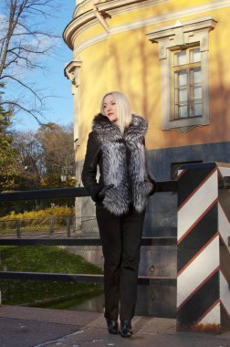 Kürklü kız güneşli bir günde şehirde dolaşır (poster modeli))