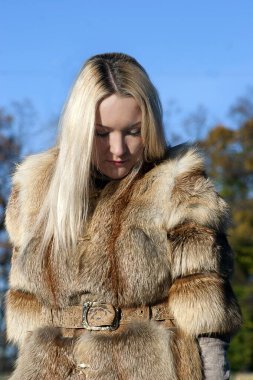 Kürklü kız güneşli bir günde şehirde dolaşır (poster modeli))