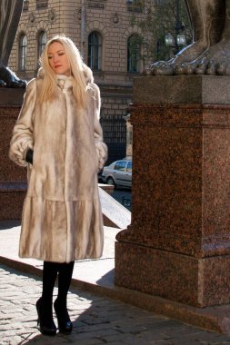 Kürklü kız güneşli bir günde şehirde dolaşır (poster modeli))