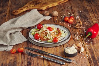 Tahta zemin üzerinde beyaz bir tabakta karidesli Sezar salatası.