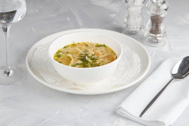 Tavuk çorbası, restoran servisi, hafif arka plan.