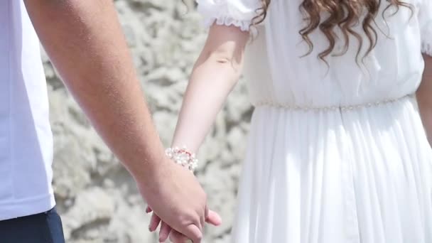 La pareja de blanco pasa por un muro de piedra. cámara lenta. vista desde atrás . — Vídeos de Stock