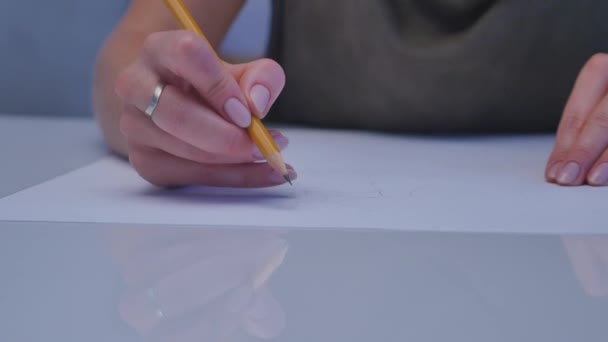 Manos humanas con lápiz escrito sobre papel sobre fondo de mesa blanco — Vídeo de stock