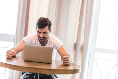 Mutlu heyecanlı adam online başarıyı kutluyor dizüstü bilgisayara bakıyor..