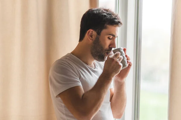 照片上是一位从容的商人，他在家里的窗户边喝咖啡. — 图库照片
