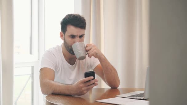 İş adamının sıcak kahve içerken akıllı telefon kullandığı 4K video.. — Stok video