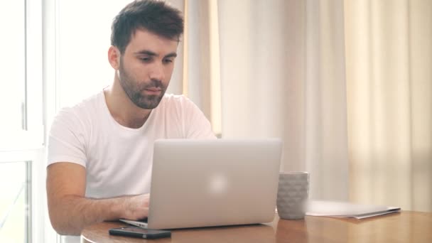 Vidéo ralenti 4k de l'homme assis à la table travaillant avec un ordinateur portable. — Video