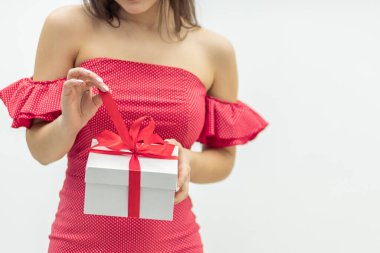 Tatil kutlaması konsepti. İçinde ne olduğunu öğrenmek için bir hediye kutusu tutan meraklı genç bir kadın..