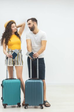 Bagajı olan mutlu bir kadın ve elinde pasaportları ve seyahat bileti olan kocası..