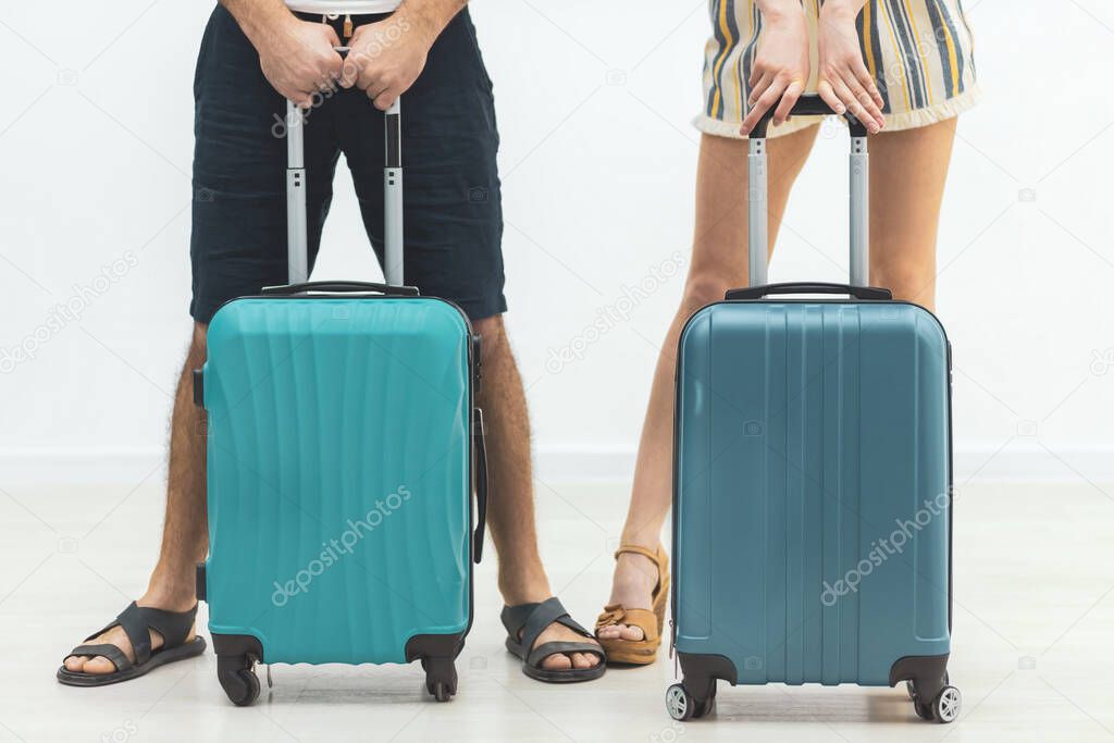 Cropped view of couple of tourists holding hands and pulling their luggage.