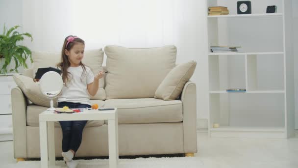 4k βίντεο του μικρού κοριτσιού κάθεται σε λευκό καναπέ και καλώντας τη μητέρα της. — Αρχείο Βίντεο