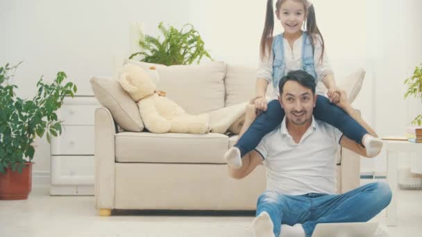 Otec drží svou krásnou dcerušku na ramenou a pak spadli na podlahu v 4K videu. — Stock video
