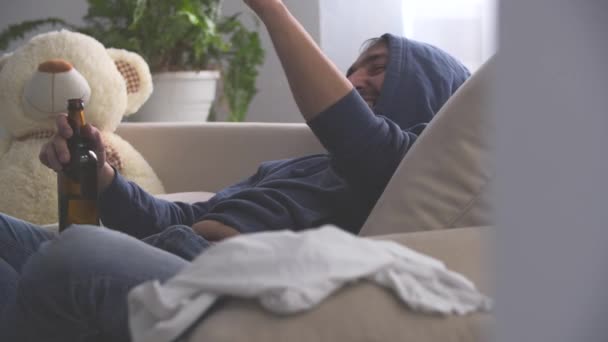 4k video donde el hombre borracho está mostrando su dedo índice y riendo acostado en el sofá. — Vídeo de stock
