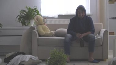 Genç sakallı bir adam oturmuş bira şişesini alıyor ve 4 bin dolarlık bir videoda kanepeye uzanıyor. Akşamdan kalma olduğu için kendini kötü hissediyor..