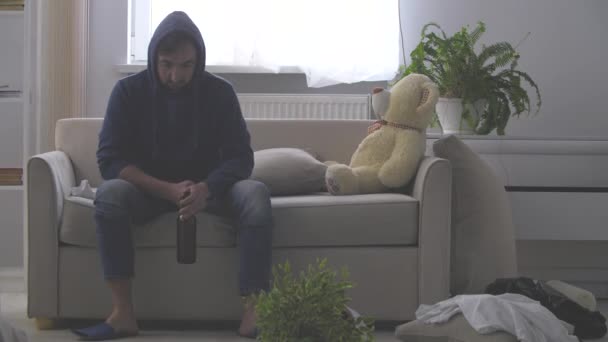 4k video donde el hombre sentado en el sofá mirando en el frente bebiendo su cerveza. — Vídeos de Stock
