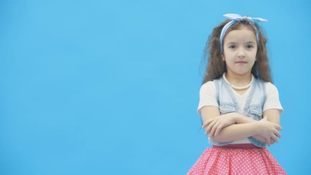 Niña tomando decisiones sobre fondo azul en video de cámara lenta 4k. — Vídeos de Stock